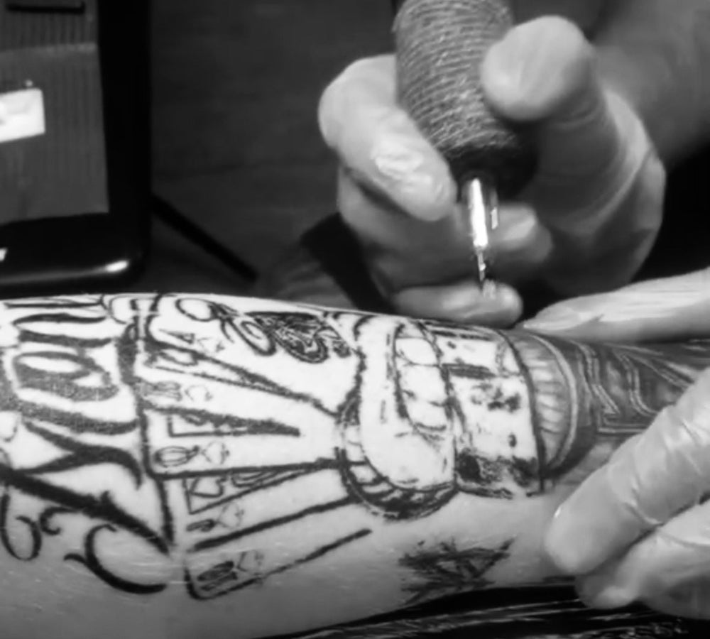 Person getting a tattoo of a detailed design on their arm.